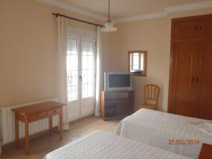 a hotel room with two beds and a television at Casa Rural El Jarral in Jarafuel