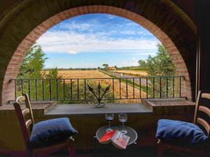 an arched window with a table and two glasses of wine at Belvilla by OYO Camillo Tosco in Valiano