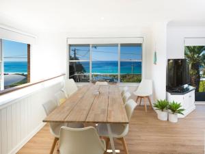 a dining room with a wooden table and views of the ocean at Aqua Palm with Sweeping One Mile Views in Forster
