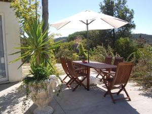 een houten tafel en stoelen met een parasol bij A Perfect villa with pool terrace and garden in Alcobaça