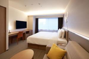 um quarto de hotel com uma cama, uma secretária e uma televisão em Holiday Inn & Suites Shin Osaka, an IHG Hotel em Osaka