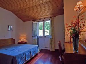a bedroom with a blue bed and a window at Quinta Das Colmeias Cottage in Santo da Serra