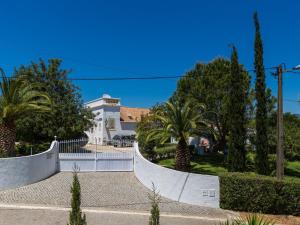une maison blanche avec des palmiers et une clôture dans l'établissement Gorgeous Holiday Home with Swimming Pool, à Odiáxere