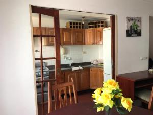 a kitchen with wooden cabinets and a table with yellow flowers at DEPARTAMENTO TORRE IV in Comodoro Rivadavia +7 photos
