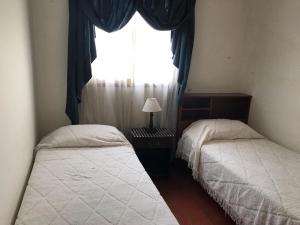 two twin beds in a bedroom with a window at DEPARTAMENTO TORRE IV in Comodoro Rivadavia