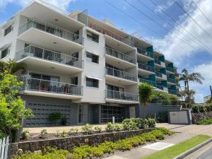 
a large white building with a view of a city at Kings Bay Apartments in Caloundra
