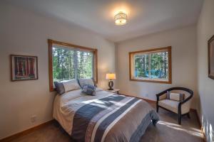 een slaapkamer met een bed en een stoel en 2 ramen bij A Blue Sky Lodge in Yosemite West