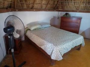a bedroom with a bed with a fan and a dresser at Cafe Maya - Casa Acalli in Zipolite