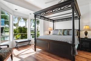 a bedroom with a black canopy bed and windows at Manatee Manor in Marco Island