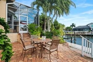 a patio with a table and chairs next to the water at Manatee Manor in Marco Island
