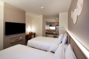 大阪市にあるホリデイ・イン＆スイーツ新大阪のベッド2台、薄型テレビが備わるホテルルームです。