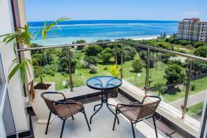 balcón con mesa, sillas y vistas al océano en EMIRATES REEF APARTMENT 8D, en Mombasa