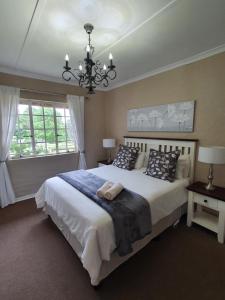 a bedroom with a large bed and a chandelier at Invermooi Estate in Nottingham Road