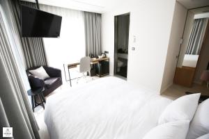 a hotel room with a white bed and a chair at Londoner Hotel Gwangan in Busan