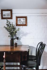 una mesa de madera con 2 sillas y un jarrón con flores en The Loft en Castlemaine