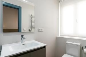 uma casa de banho com um lavatório, um espelho e um WC. em Apartamentos Leoncillos em Sevilha