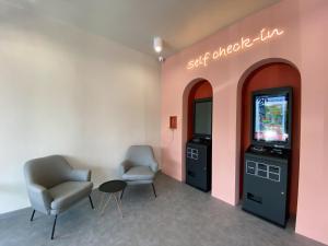 a waiting room with two chairs and a video game at Woco Hotel Kinrara in Puchong