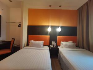 um quarto com duas camas e uma cadeira em 2 Inn 1 Boutique Hotel & Spa em Sandakan