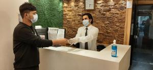 Un uomo e una donna con maschere facciali al bancone di Hotel Amisha International a Surat