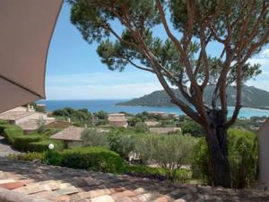 a view of a house with a tree and the ocean at Les Mini-villas de Santa-giulia in Porto-Vecchio +21 photos