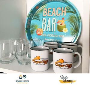 a shelf with several cups and a beach bar sign at Studios du Parc apparts Hôtel - Futuroscope in Chasseneuil-du-Poitou