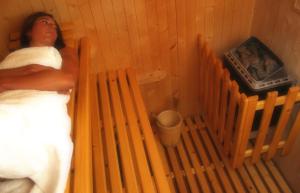 a woman sitting on a wooden bench in a bathroom at Fattoria Pieve a Salti in Buonconvento