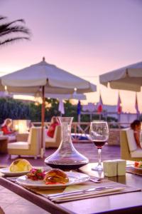 Solimar Dias Hotel في أذيليانوس كامبوس: طاولة مع طعام وكأس من النبيذ