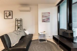 uma sala de estar com um sofá de couro preto e uma televisão em Central Melbourne CBD Lighthouse Apartment em Melbourne
