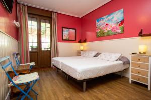 サン・セバスティアンにあるペンション アマユールの赤い壁のベッドルーム1室、ベッド1台、椅子1脚が備わります。
