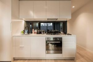 uma cozinha com armários brancos e um fogão em Central Melbourne CBD Lighthouse Apartment em Melbourne