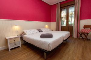 a bedroom with a bed with a pink wall at Pensión Amaiur in San Sebastián