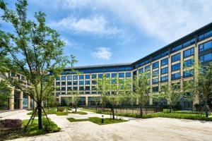 un edificio de oficinas con árboles delante de él en Q-Box Hotel Shanghai Sanjiagang -Offer Pudong International Airport and Disney shuttle, en Shanghái