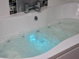 a bath tub with blue water in it at Pant Glas Barn in Llanbrynmair
