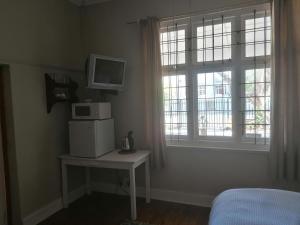 a bedroom with a microwave on a table and a window at Villa de Karoo Guest House in Oudtshoorn