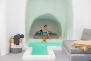 una mujer sentada en una cama en una piscina en Nano Suites en Éxo Goniá
