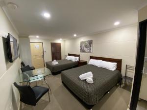 ein Hotelzimmer mit zwei Betten und einem Glastisch in der Unterkunft Balranald Club Motel in Balranald