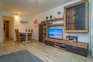 ein Wohnzimmer mit einem TV und einem Esstisch in der Unterkunft Falkennest 1 in Westerland