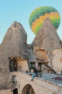 a person sitting on a ledge with a hot air balloon at Kelebek Special Cave Hotel & Spa in Goreme