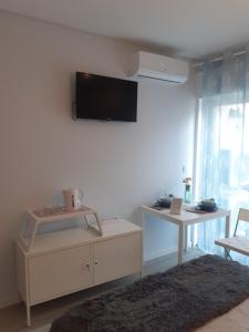 een woonkamer met een flatscreen-tv aan de muur bij Porto Beach Rooms in Porto