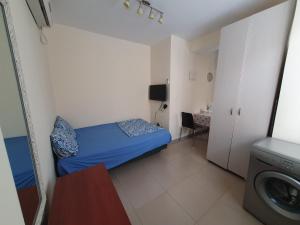 um pequeno quarto com uma cama azul e uma máquina de lavar roupa em Apartments Petah Tiqwa - Bar Kochva Street em Petah Tiqwa