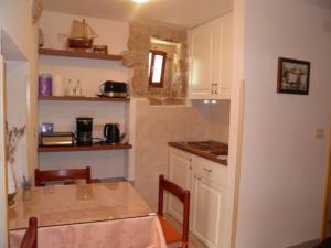 a kitchen with a table and chairs and a counter top at Apartman DEJO in Mošćenička Draga