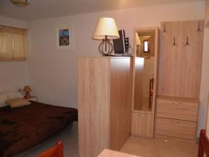 a bedroom with a bed and a dresser with a lamp at Apartman DEJO in Mošćenička Draga