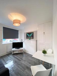 ein Wohnzimmer mit einem TV, einem Tisch und Stühlen in der Unterkunft The Baltic Townhouses by Serviced Living Liverpool in Liverpool