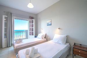 two beds in a room with a view of the ocean at Bellezza Del Mare in Amoudi