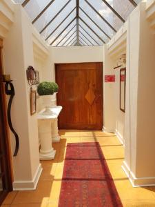 a hallway with a wooden door and a red rug at Dormio Manor Guest Lodge in Secunda