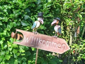 two birds sitting on top of a sign at Ferienhof Petersen - Gastfreundschaft im hohen Norden in Großenwiehe
