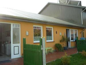 a small yellow house with a green fence at Ferienhof Petersen - Gastfreundschaft im hohen Norden in Großenwiehe