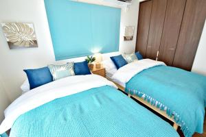 two beds in a room with blue and white at ゲストハウスえらぶ〜 in Wadomari