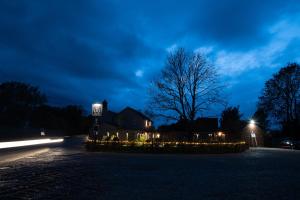 The Three Horseshoes في Briston: ضوء المنزل في الليل مع وجود علامة مضاءة