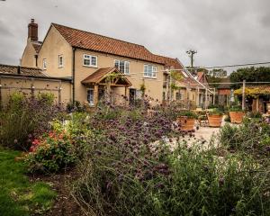 um jardim em frente a uma casa com flores em The Three Horseshoes em Briston